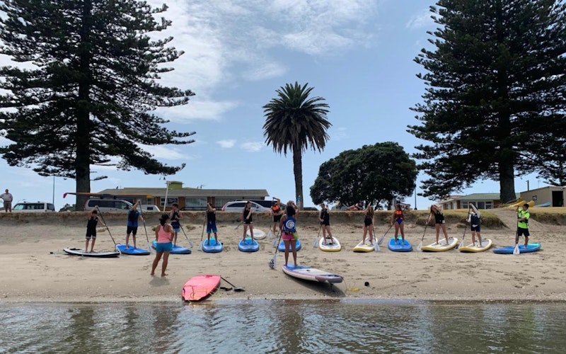 A group learning how to stand up paddle